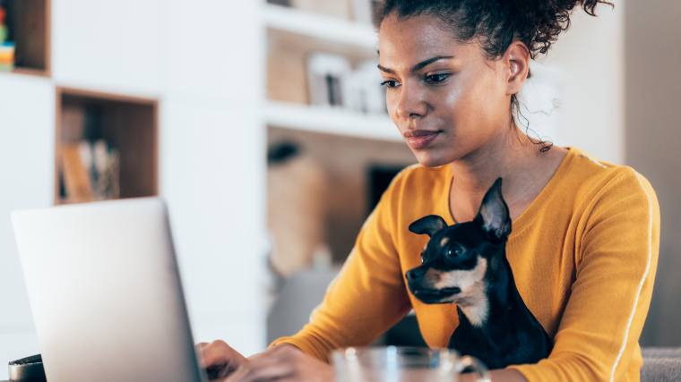 woman with dog sitting in front of laptop