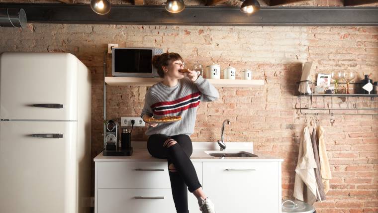 young woman eating pizza in her kitchen