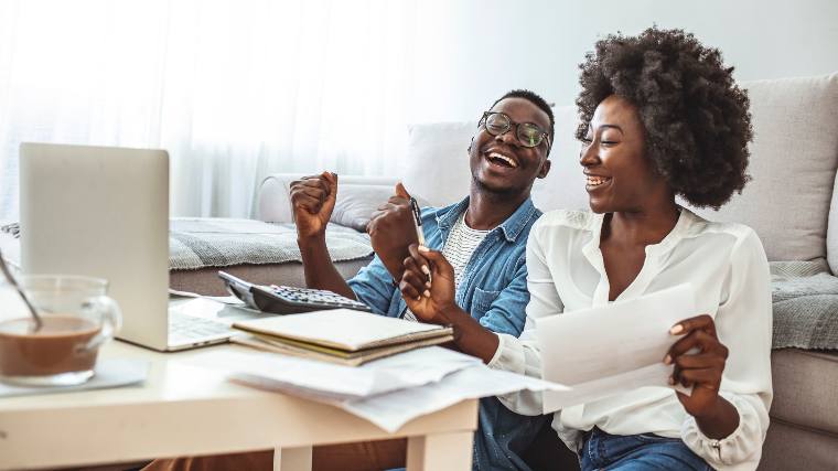 Young couple celebrating while reviewing finances.