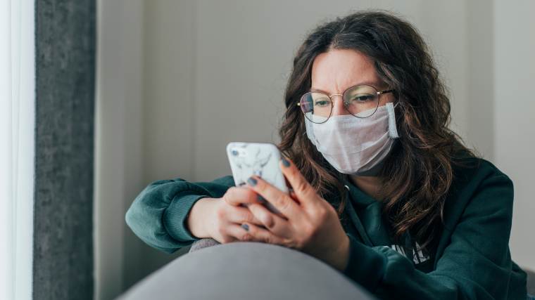 woman with mask checking her phone