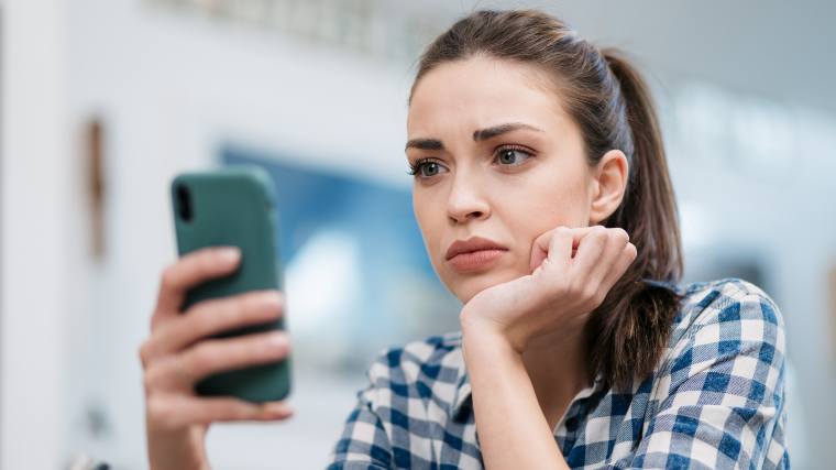 Distressed woman looking at cellphone.