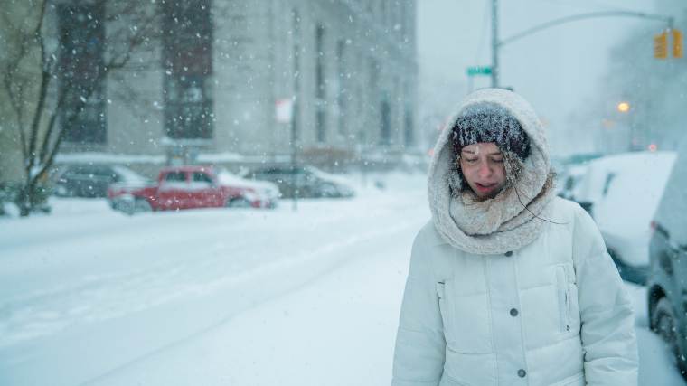 woman walking through city during major snow storm