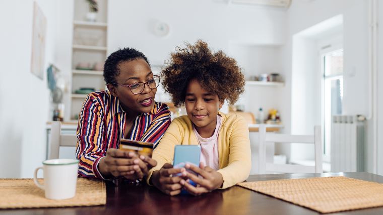 Grandmother and granddaughter using credit card to make purchase.