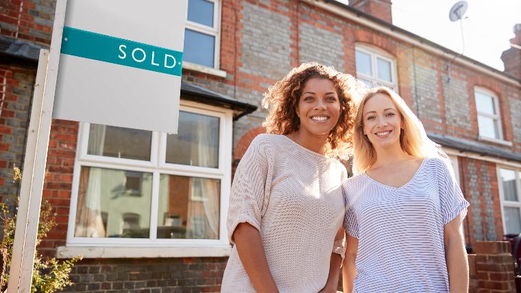 Couple standing in front of new home.