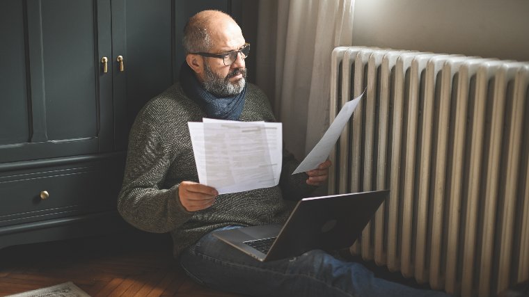 Man sitting on floor reading documents.