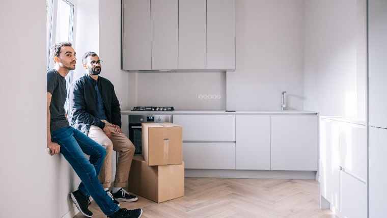 Two men in empty kitchen with moving boxes.