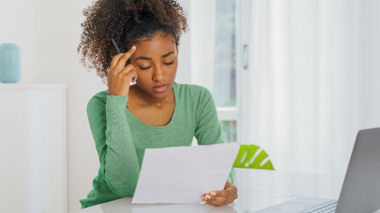 Distraught young woman reading bill.