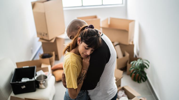 Couple hugging in room full of packing boxes.