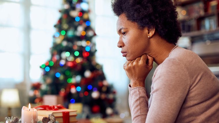 Concerned woman in front of Christmas tree.