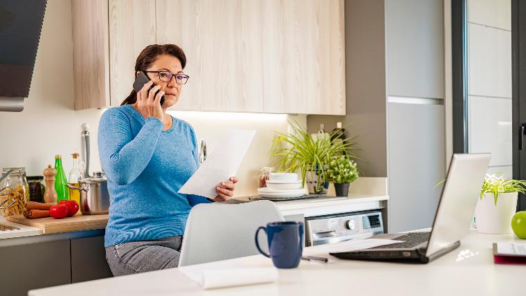 Woman speaking on the phone and holding bill.