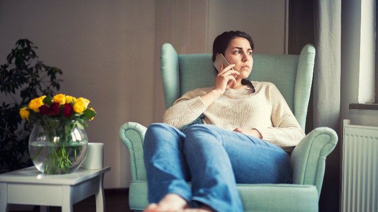 Unhappy woman making phone call inside home.