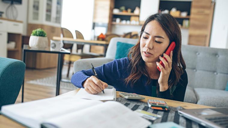 Woman taking notes while on phone call.