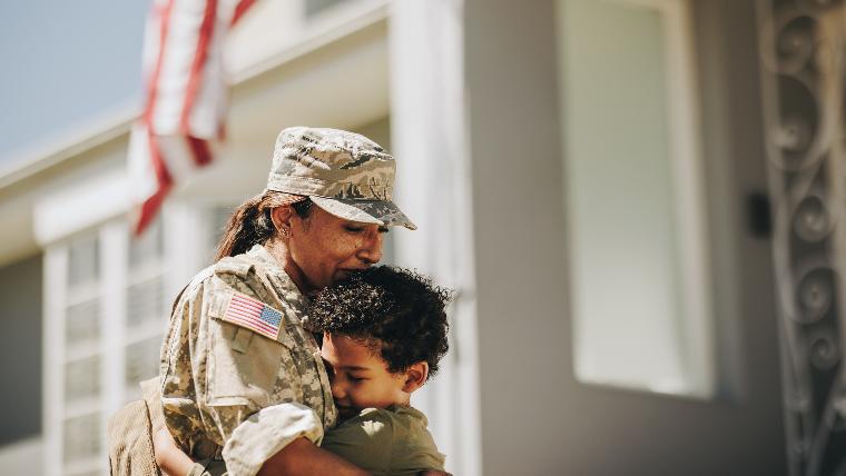 Military mom hugs young son.