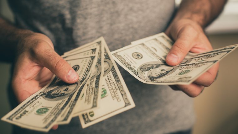 Man counting a small collection of $100 bills.