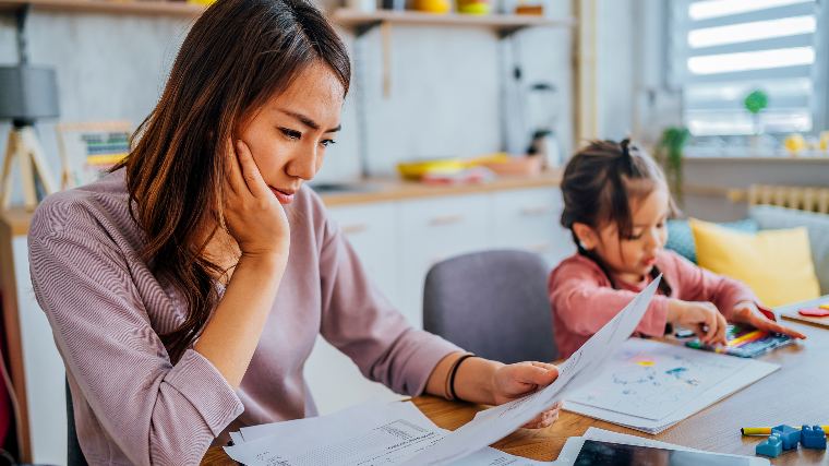 Mom reviewing bills at kitchen table.