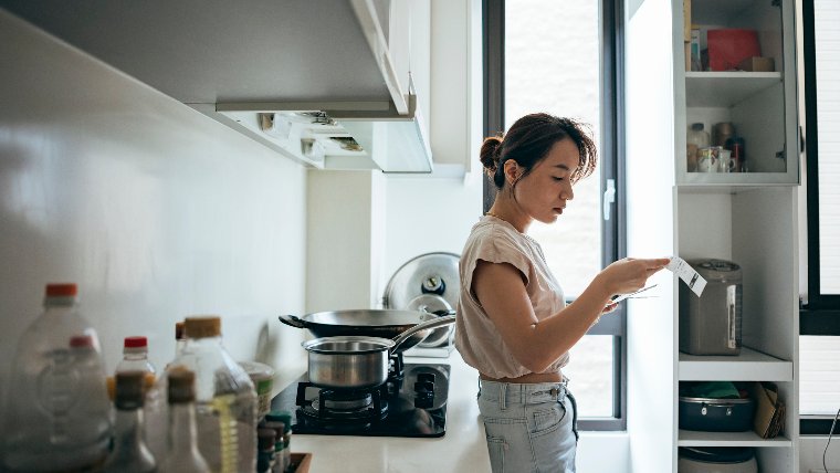 Woman reading receipt in her kitchen.