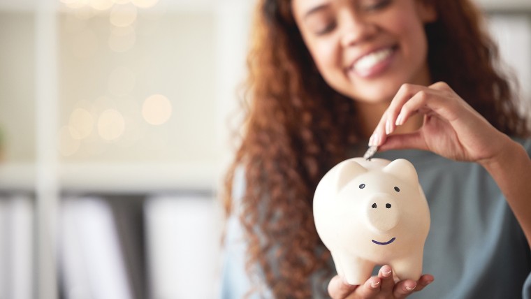 Woman putting money into a piggy bank.