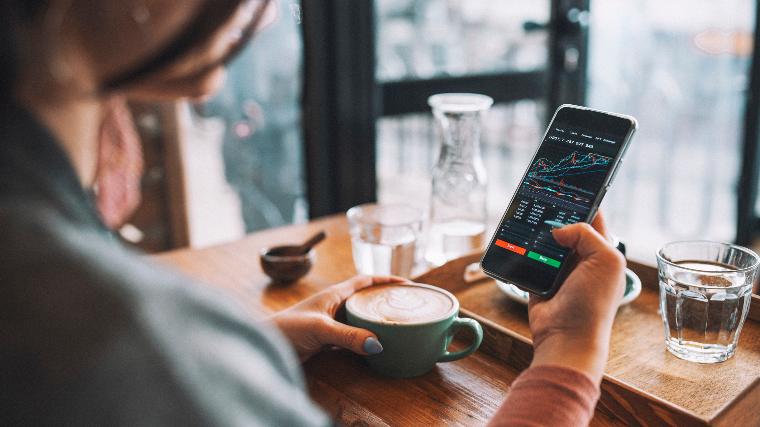 Woman trading stocks on cellphone.