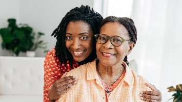 Senior woman and her young adult daughter smiling into the camera.
