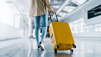 Woman with rolling luggage walking through airport.