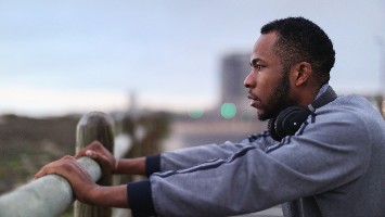 Contemplative man standing next to fence.