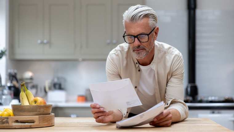 White haired man reading letter.