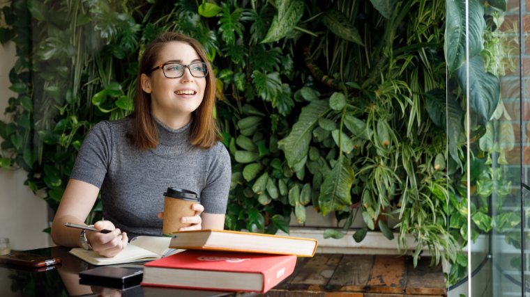Young woman drinks coffee and takes notes.