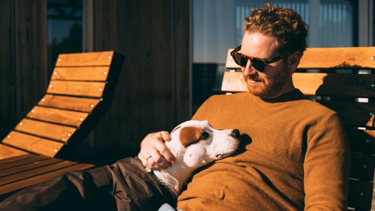 Man sitting outside and relaxing with his dog.