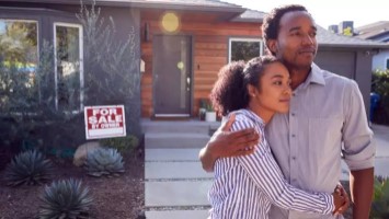 Young couple standing in front of home that is for sale.