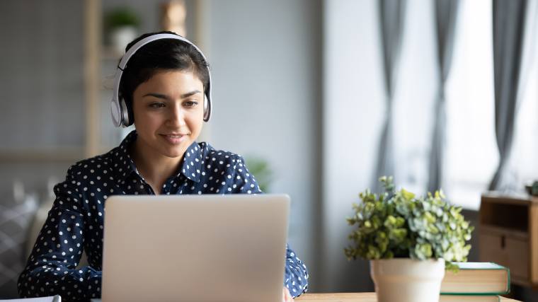 young woman using a laptop and wearing headphones