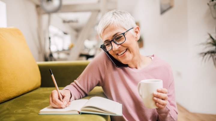 woman taking notes while talking on the phone