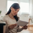 Concerned woman reading letter.