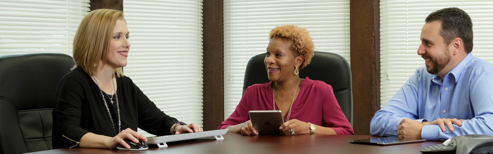 Karen Soileau sits at a conference table with two smiling coworkers at MMI.